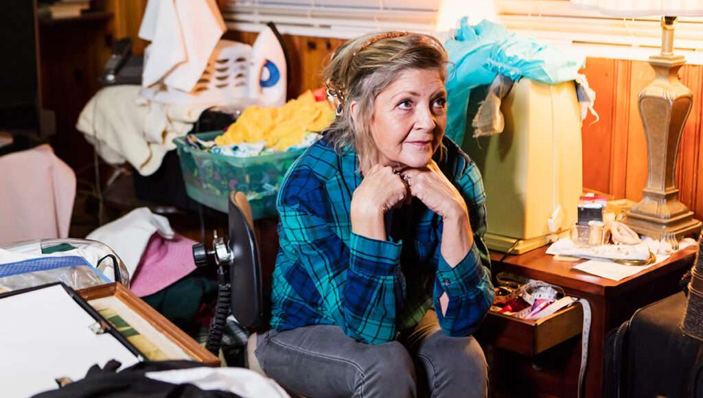 Woman sitting in room filled with items