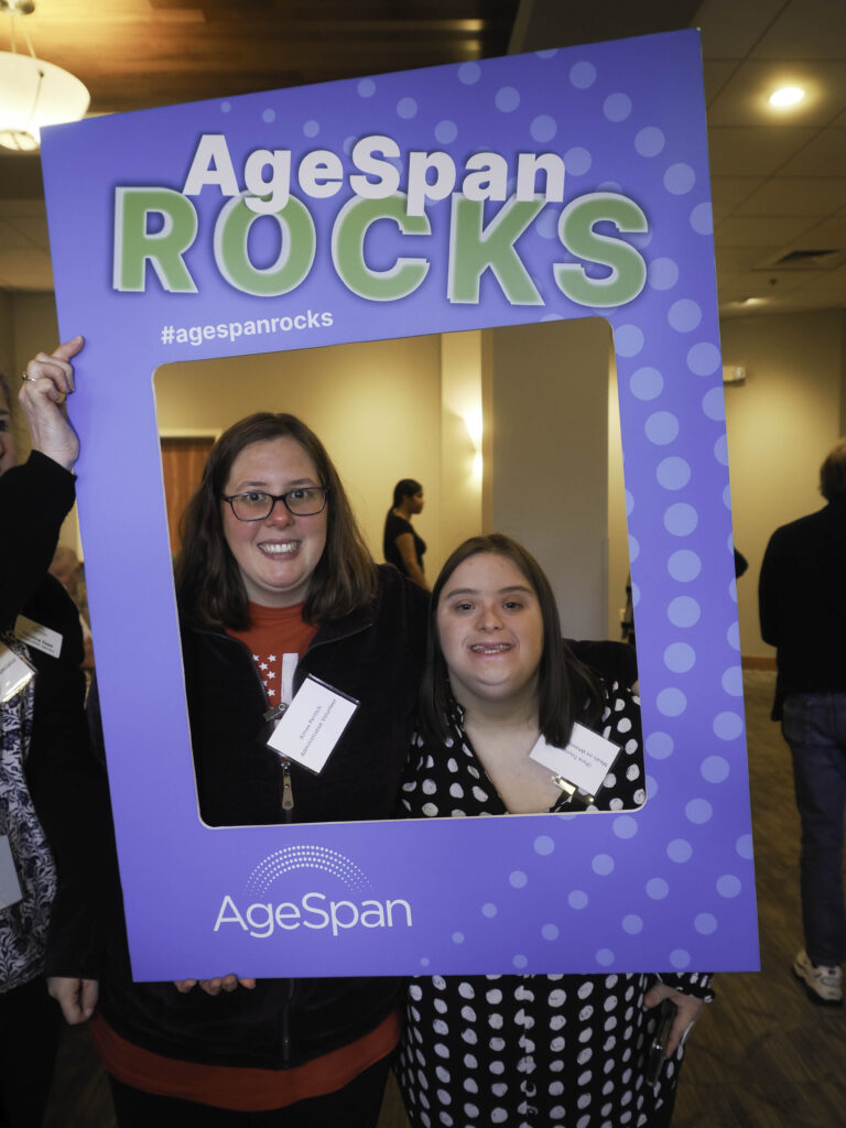 Two volunteers pose in AgeSpan rocks frame