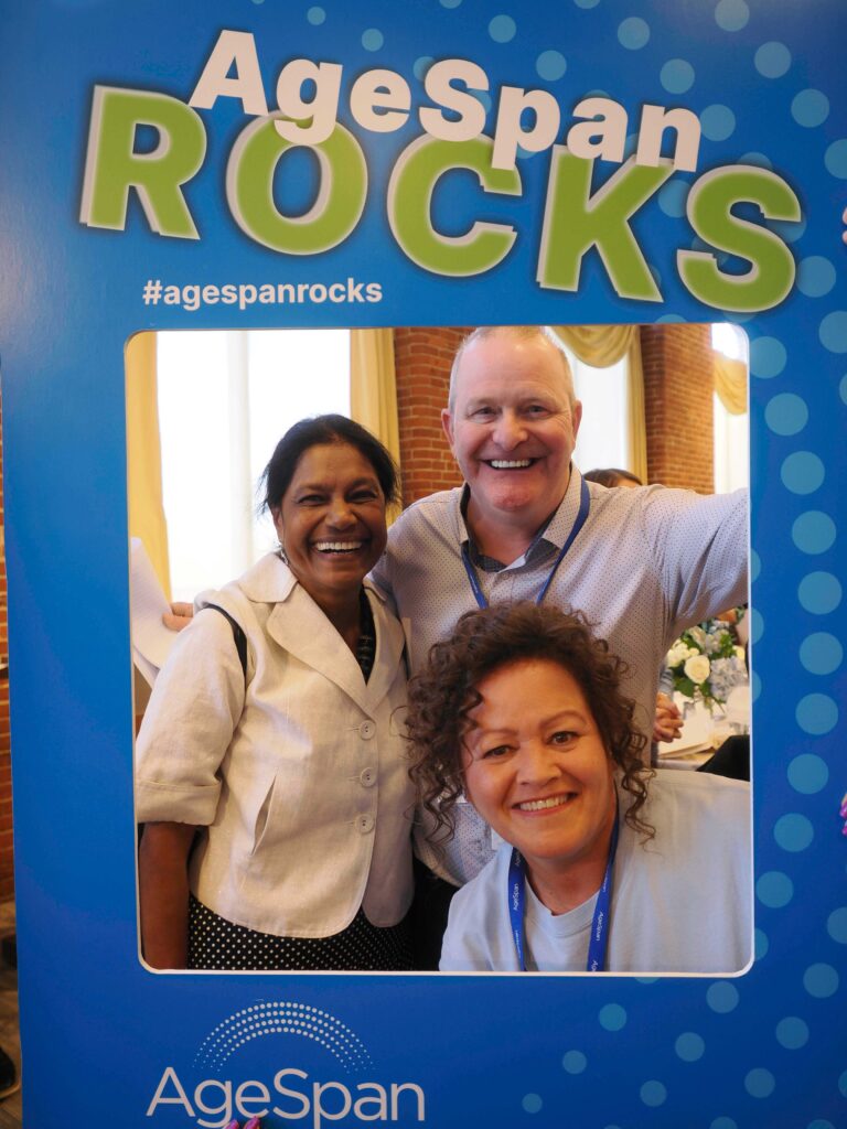 Three people pose in AgeSpan rocks frame