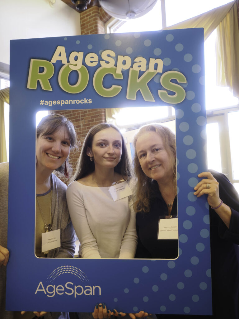 Two volunteers and Rebecca Kay pose in AgeSpan rocks frame