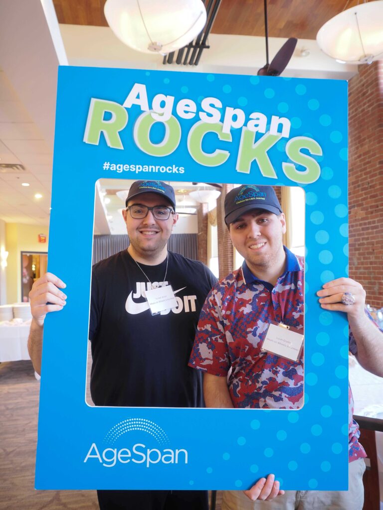Two volunteers pose in AgeSpan rocks frame