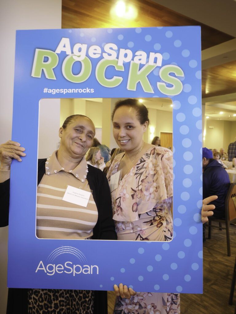 Two volunteers pose in AgeSpan rocks frame