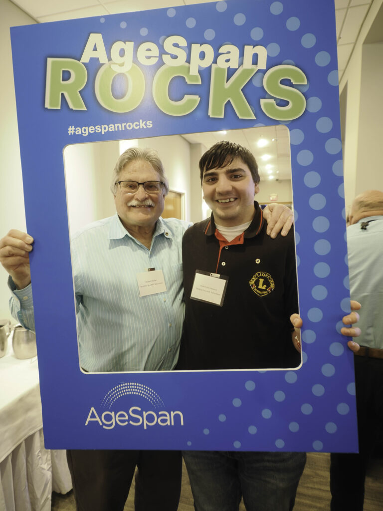 Two volunteers pose in AgeSpan rocks frame