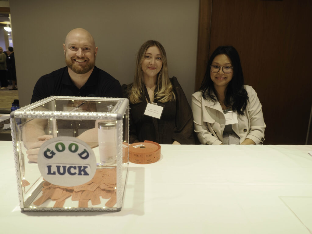 Three people from the AgeSpan HR team pose with raffle tickets in foreground