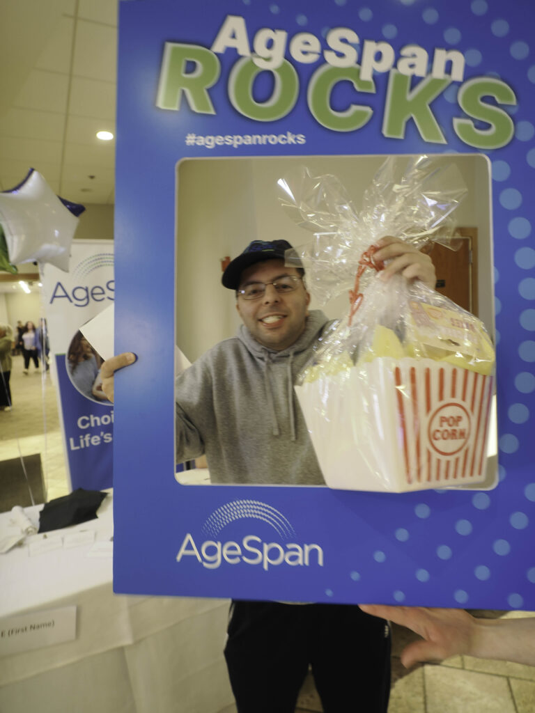 A man with glasses and a popcorn box poses in AgeSpan rocks frame